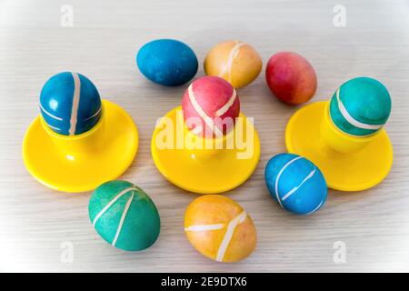 Colorful painted homemade easter eggs with modern pattern on yellow coasters on wooden table. Easter decoration, easter background. Stock Photo