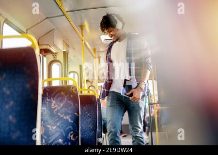 Young modern Afro-American man standing in a public transport and listening to the music. Stock Photo