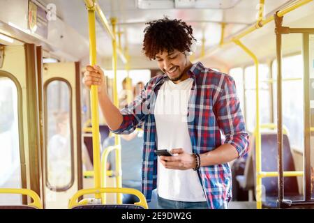 Young modern Afro-American man standing in a public transport and listening to the music. Stock Photo
