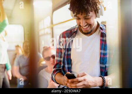 Young modern Afro-American man sitting alone in a public transport and listening to the music. Waiting for bus to move on. Stock Photo