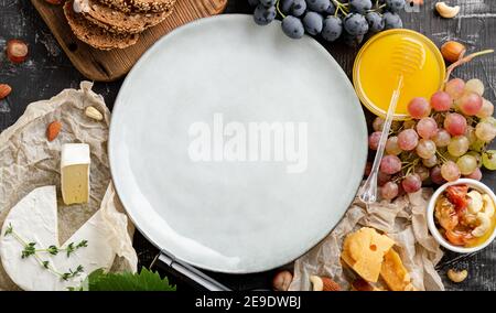 Round Plate blank or frame on grocery. Restaurant menu, template recipe. Mock up plate on full of food various table. Ceramic dish served in center Stock Photo