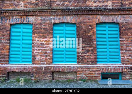 Brick wall with three freshly painted light blue window shutters Stock Photo