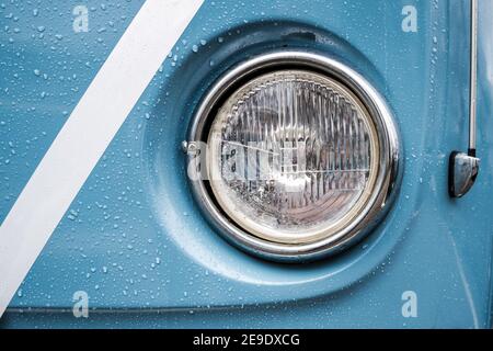 Blue wedding camper van rain on paint and round glass headlight with  H4 shiny polished chrome surround, radio arial to the side white ribbon Stock Photo