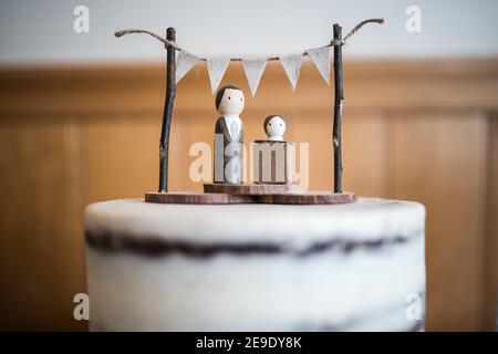 Bride groom wedding cake topper little bunting and showing the bride without dress the saying you would look beautiful in a cardboard box anything Stock Photo