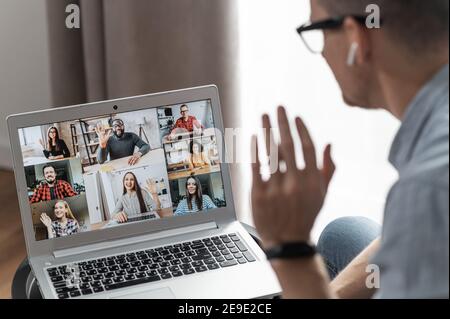 Group of diverse multiracial people on the laptop screen, a young man is waving hello to colleagues, employees online. Video conference, brainstorm Stock Photo