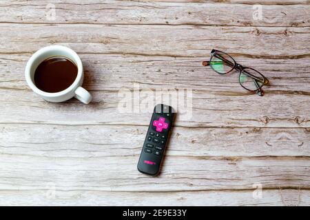 02-04-2021 Portsmouth, Hampshire, UK A Pink Now TV remote control laid on a table or desk next to glasses and a coffee Stock Photo