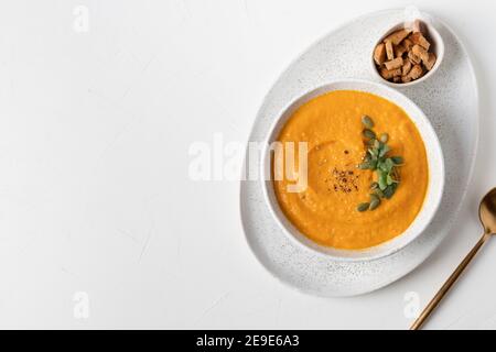Pumpkin soup served crackers and microgreens isolated on white table. View from above. Stock Photo