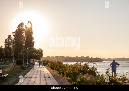 BELGRADE, SERBIA - AUGUST 29, 2020: people walking and running on a pedestrian waterfront of the Danube quay in Belgrade, Serbia, at dusk, in front of Stock Photo