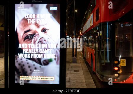 A government NHS (National Heath Service) ad at a bus stop displays the face of a Covid patient, urging Londoners to stay at home and to socially distance, outside the Royal Courts of Justice, on 2nd February 2021, in London, England. Stock Photo