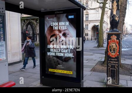 A government NHS (National Heath Service) ad at a Bus stop near the Royal Courts of Justice displays the face of a Covid patient, urging Londoners to stay at home and to socially distance, outside the Royal Courts of Justice, on 2nd February 2021, in London, England. Stock Photo