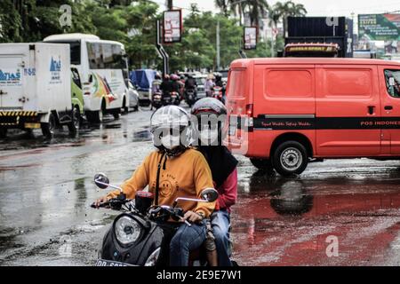 Makassar, South Sulawesi, Indonesia. 4th Feb, 2021. Motorcycle riders wear a mask while crossing a traffic jam due to flooding in Makassar City, Indonesia. Several main roads in the area have been flooded due to increased rainfall in the last few days. Credit: Herwin Bahar/ZUMA Wire/Alamy Live News Stock Photo