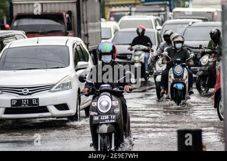 Makassar, South Sulawesi, Indonesia. 4th Feb, 2021. Motorcycle riders wear a mask while crossing a traffic jam due to flooding in Makassar City, Indonesia. Several main roads in the area have been flooded due to increased rainfall in the last few days. Credit: Herwin Bahar/ZUMA Wire/Alamy Live News Stock Photo