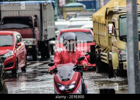 Makassar, South Sulawesi, Indonesia. 4th Feb, 2021. Motorcycle riders wear a mask while crossing a traffic jam due to flooding in Makassar City, Indonesia. Several main roads in the area have been flooded due to increased rainfall in the last few days. Credit: Herwin Bahar/ZUMA Wire/Alamy Live News Stock Photo