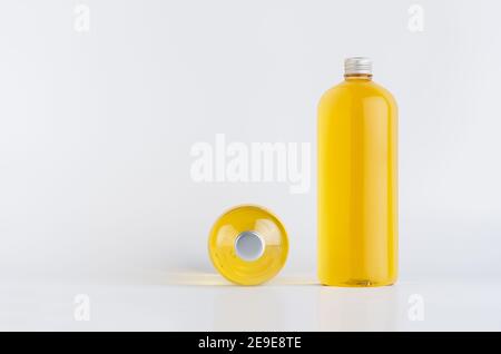 Set of two transparent plastic tall bottles standing and lying with orange liquid, oil or cosmetic produce and silver cap, mockup on white background, Stock Photo