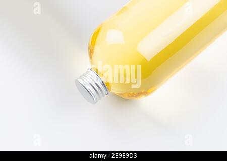 Top part of transparent lying plastic bottle with yellow liquid with silver cap, top view, closeup, copy space. Stock Photo