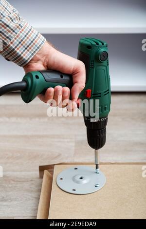 Furniture assembly process, master collects table furniture using drill tool instrument. Moving, home improvement, furniture repair renovation. Stock Photo