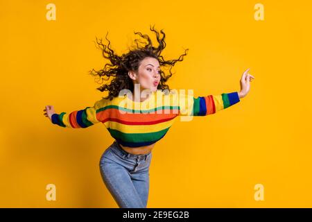 Photo of childish lady wearing casual colorful sweater dancing looking pointing empty space lips pouted isolated yellow color background Stock Photo