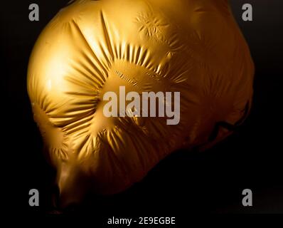 A Golden Balloon Loses Air And Its Sagging Skin Is Full Of Shrinkage In a-golden-balloon-loses-air-and-its-sagging-skin-is-full-of-shrinkage-in