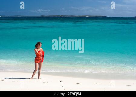 Woman tourist standing on a secluded sandy beach in a beautiful Emerald Bay (Mer d'Emeraude), island archipelago, Antsiranana, Madagascar Stock Photo