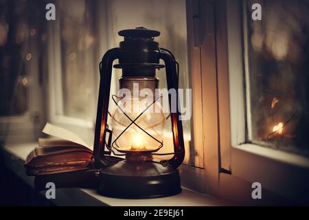 Kerosene lamp and old books on the windowsill. Stock Photo