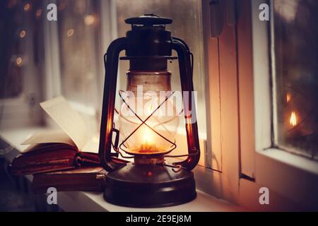 Kerosene lamp and old books on the windowsill. Stock Photo
