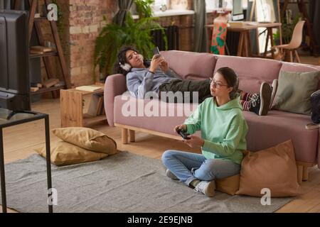 Two teenagers sitting in the living room and playing video game together Stock Photo