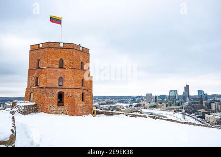 Gediminas Tower or Castle, the remaining part of the Upper Medieval Castle in Vilnius, Lithuania with Lithuanian flag and city in winter day with snow Stock Photo