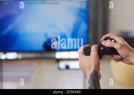 Close-up of man using joystick to play video game on the big screen of TV Stock Photo