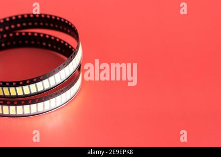 Yellow Led strip coil packaging closeup isolated on red background. Spare part for repair lamp or latern. Diode tape in the package Stock Photo