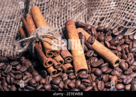 Coffee beans and cinnamon sticks lying on a table with a rough bag Stock Photo