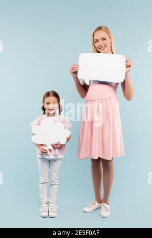 full length of pregnant mother and kid holding thought and speech bubbles on blue Stock Photo