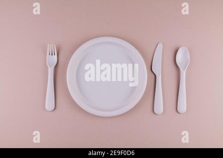 set of plastic dishes spoon fork knife gray plate on the table Stock Photo