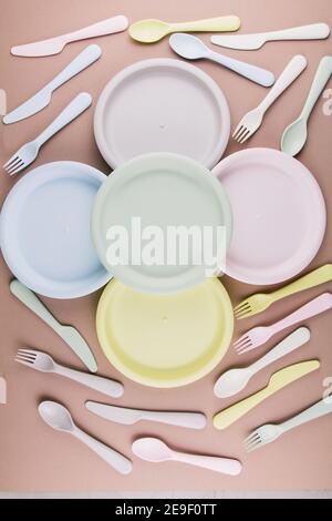 set of plastic colored dishes with a plate fork spoon knife on the table eco-friendly tableware Stock Photo