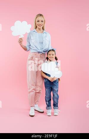 full length of happy mother and daughter holding thought bubbles on pink Stock Photo