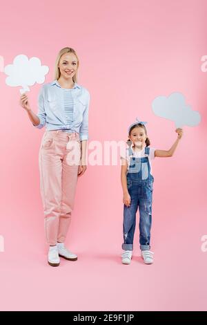 full length of cheerful mother and daughter holding thought bubbles on pink Stock Photo