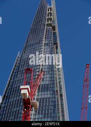 view of the Shard building against a deep blue sky with red tower cranes in the foreground Stock Photo