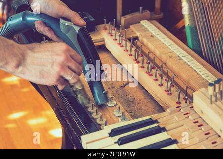 Setting up an old piano. The master repairs an old piano. Deep cleaning the piano. Hands of professional worker repairing and tuning an old piano Stock Photo