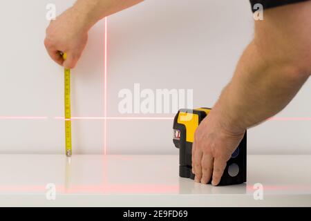 the worker marks right angles and lines during interior measurements Stock Photo