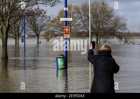 Duisburg, NRW, Germany. 04th Feb, 2021. A woman takes snaps of the flooding. Water levels on the River Rhine have risen to 9.25 metres at Ruhrort near the port of Duisburg. The flood situation North Rhine-Westphalia remained tense on Thursday with water levels expected to rise further along the River Rhine in Duisburg, as well as Düsseldorf, Wesel and Cologne, where ships can now no longer operate. Credit: Imageplotter/Alamy Live News Stock Photo