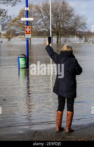 Duisburg, NRW, Germany. 04th Feb, 2021. A woman takes snaps of the flooding. Water levels on the River Rhine have risen to 9.25 metres at Ruhrort near the port of Duisburg. The flood situation North Rhine-Westphalia remained tense on Thursday with water levels expected to rise further along the River Rhine in Duisburg, as well as Düsseldorf, Wesel and Cologne, where ships can now no longer operate. Credit: Imageplotter/Alamy Live News Stock Photo
