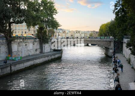 Local Parisians enjoy early evening strolling and relaxing on the banks of Seine river near the Ile de la Cite in Paris, France.