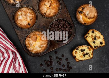 Chocolate chip muffins in a muffin tin and on the counter