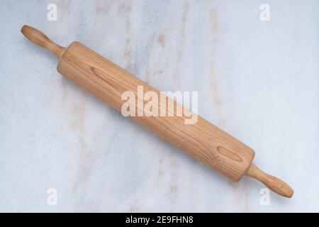 A photograph of a bakers wooden rolling pin on a pastry marble board Stock Photo