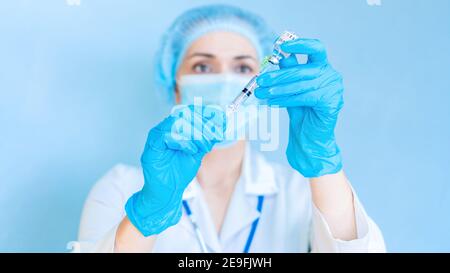 An exciting photo of a doctor preparing to inject with the Covid-19 coronavirus vaccine. The doctor holds the syringe and medicine at eye level. The c Stock Photo