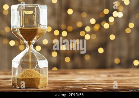 Hourglass on wooden desk against blurred lights Stock Photo