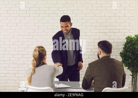 Happy African-American man shaking hands with HR managers after getting job at the company Stock Photo