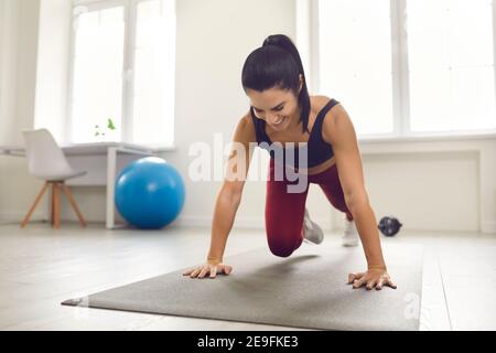 Young smiling fitness lady making mountain climbing on mat during sports workout Stock Photo