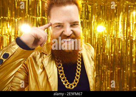 Happy confident rich guy looking at camera and touching his temple with index finger Stock Photo
