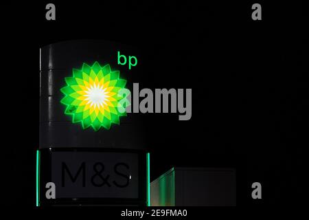 London, United Kingdom - February 01, 2019: Green and Yellow bp sun sign glowing in night on one of their petrol station at Lewisham. British Petroleu