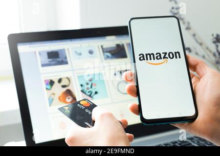 Kyiv, Ukraine - Feb. 02, 2021: Purchase of goods in the Amazon online store using a smartphone and laptop and a credit card. Stock Photo